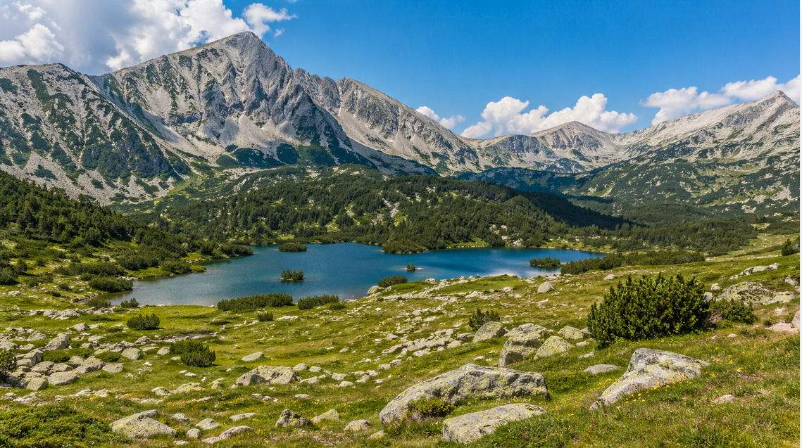 Parco del Pirin in Bulgaria con lago alpino, prati e alte montagne rocciose